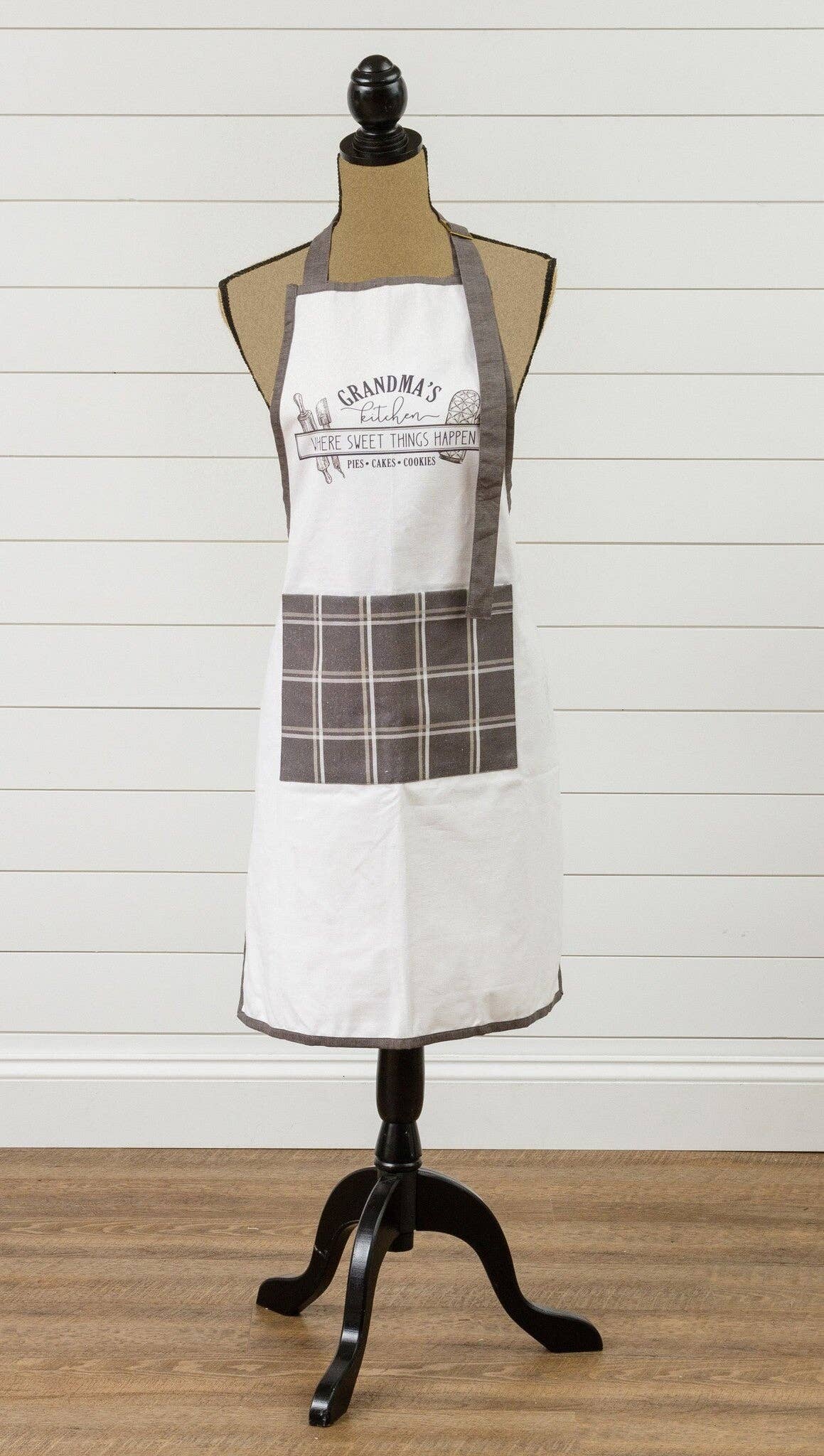 White apron with plaid design on a mannequin against a wooden floor and white wall background